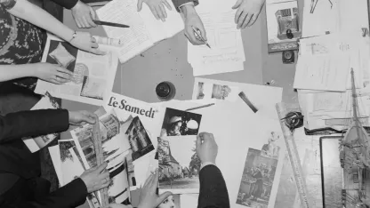 Des gens travaillant sur une table remplie de revues et de journaux.